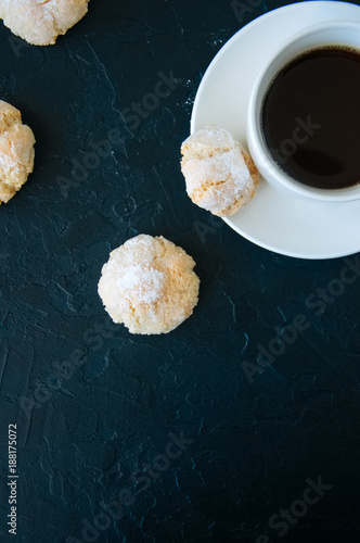 Cup of strong coffee and amaretti cookies on a black background