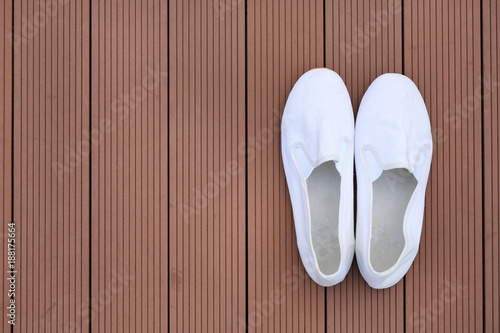 White casual shoes on wood plank background with copy space. Top view.