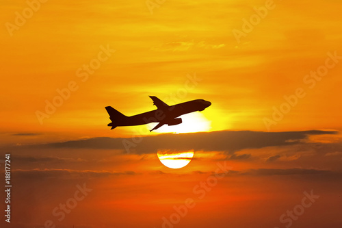 Airplane fly on sunset sky.