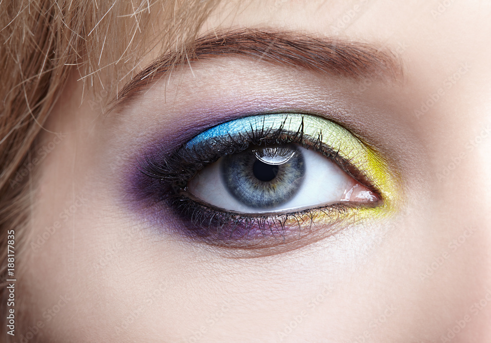 Closeup macro image of human female eye with violet, blue and and yellow makeup Closeup macro image of human female eye with violet, blue and and yellow makeup