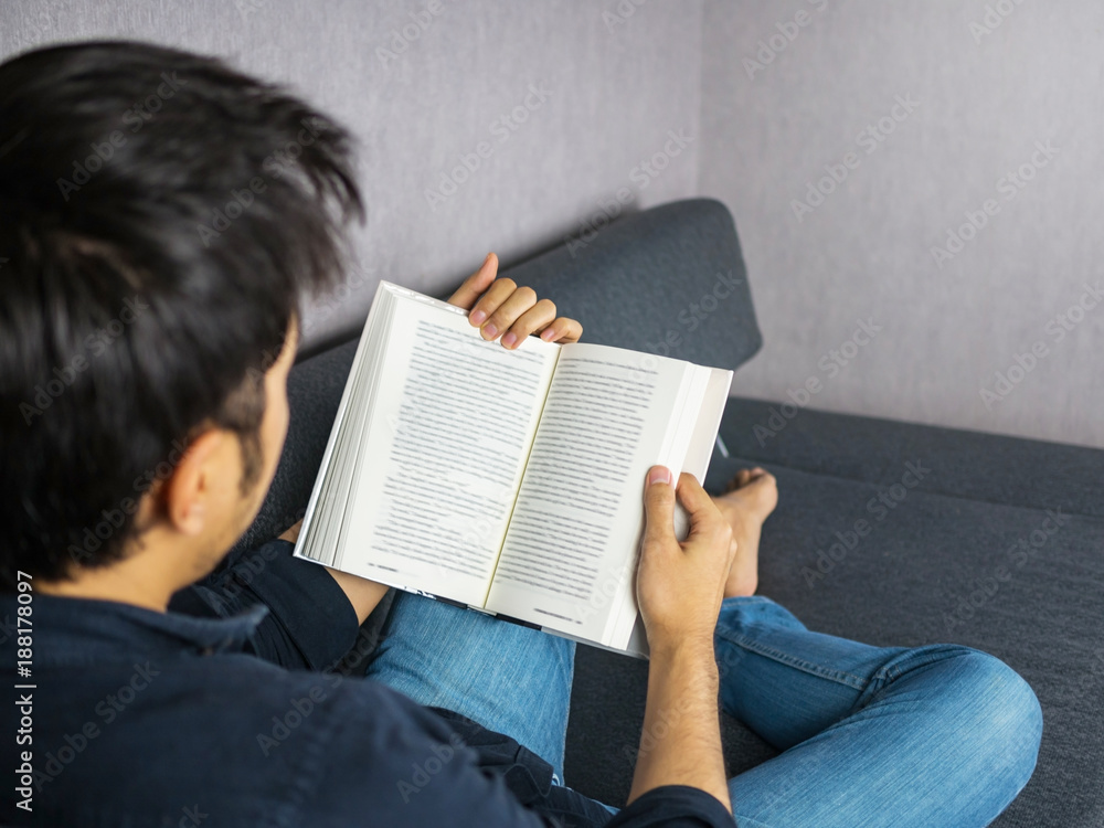 Naklejka premium Man reading book on sof