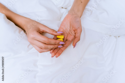 woman holding earplugs on the bed background