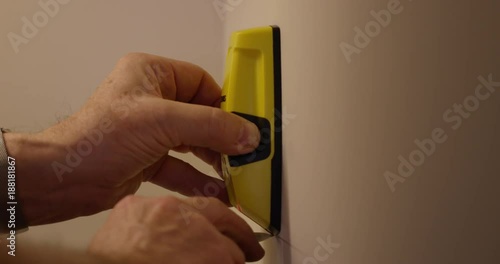 Man marks where stud is behind wall using stud finder - construction
