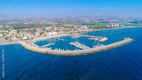 Aerial bird's eye view of Zygi fishing village port, Larnaca, Cyprus. The fish boats moored in the harbour with docked yachts and skyline of the town near Limassol from above.