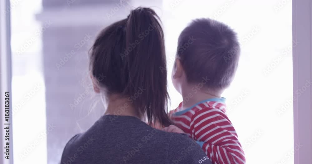 Toddler boy and mom look out window into snowy exterior Stock Video ...