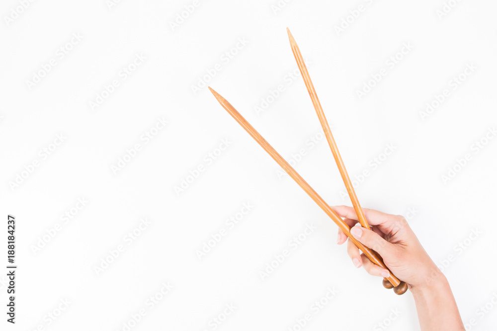 Woman hand with two wooden knitting needles over white background