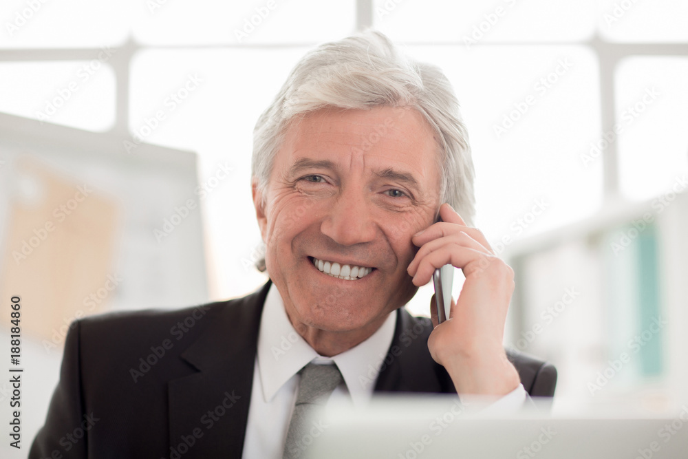 Aged businessman or director looking at camera with smile while talking by smartphone Aged businessman or director looking at camera with smile while talking by smartphone