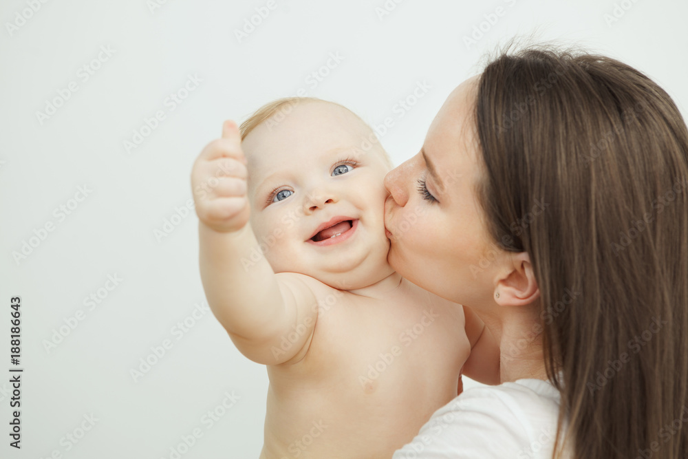 Mother kisses her adorable toddler in cheek, enfant posing Mother kisses her adorable toddler in cheek, enfant posing