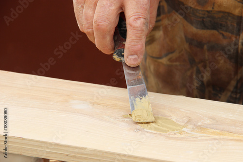 Putty knife in old man's hand. Removing paint from a wood surface. Preparation of boards before impregnation with varnish. Application of putty. Copy space for text photo