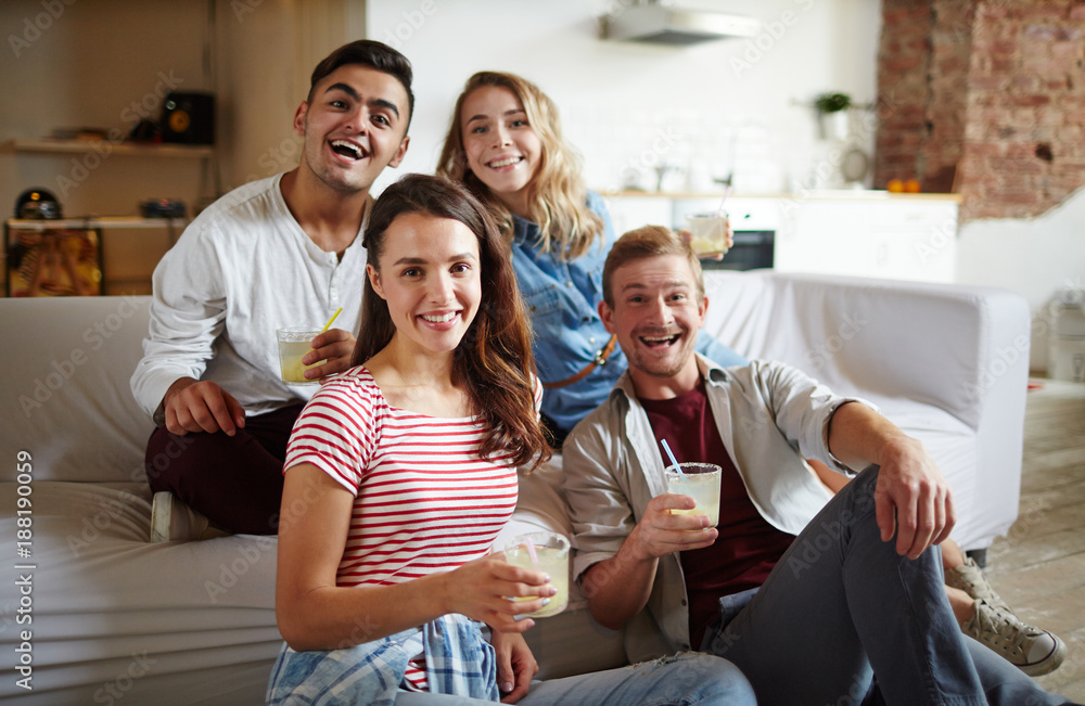 © pressmaster - Two happy couples with drinks looking at camera while having fun at home