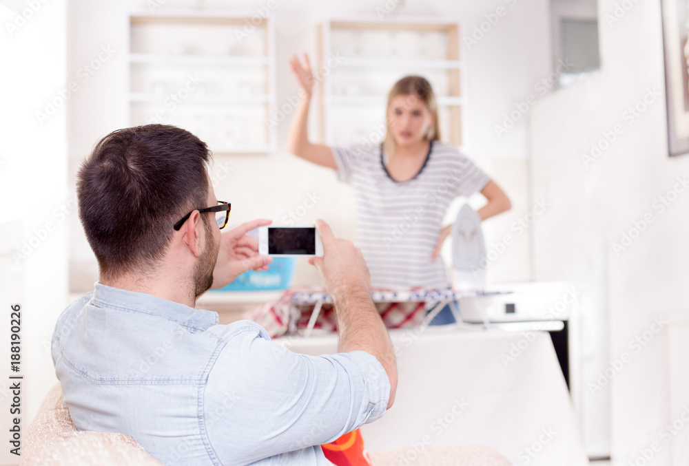 Handsome man capturing wife while ironing Handsome man capturing wife while ironing