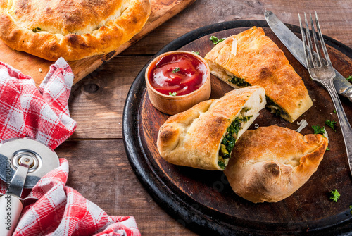 Italian food, closed pizza calzone with Spinach and Cheese, wooden background, copy space photo