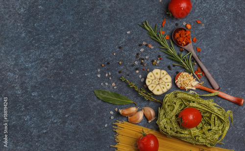Selection of spices, pasta, herbs and greens. Ingredients for cooking pasta. Dark background, top view, copy space.