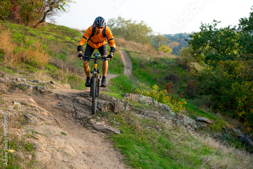 Fototapeta Naklejka Na Ścianę i Meble -  Cyclist in Orange Riding the Mountain Bike on the Autumn Rocky Trail. Extreme Sport and Enduro Biking Concept.
