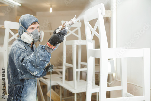 Foto Man painting chair into white paint in respiratory mask
