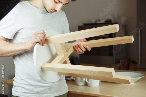 Man holding in hands wooden stool, carefully examining seat