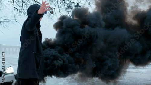 A young man in a black jacket reads rap on the background of an expensive white carthe effect of black smoke photo