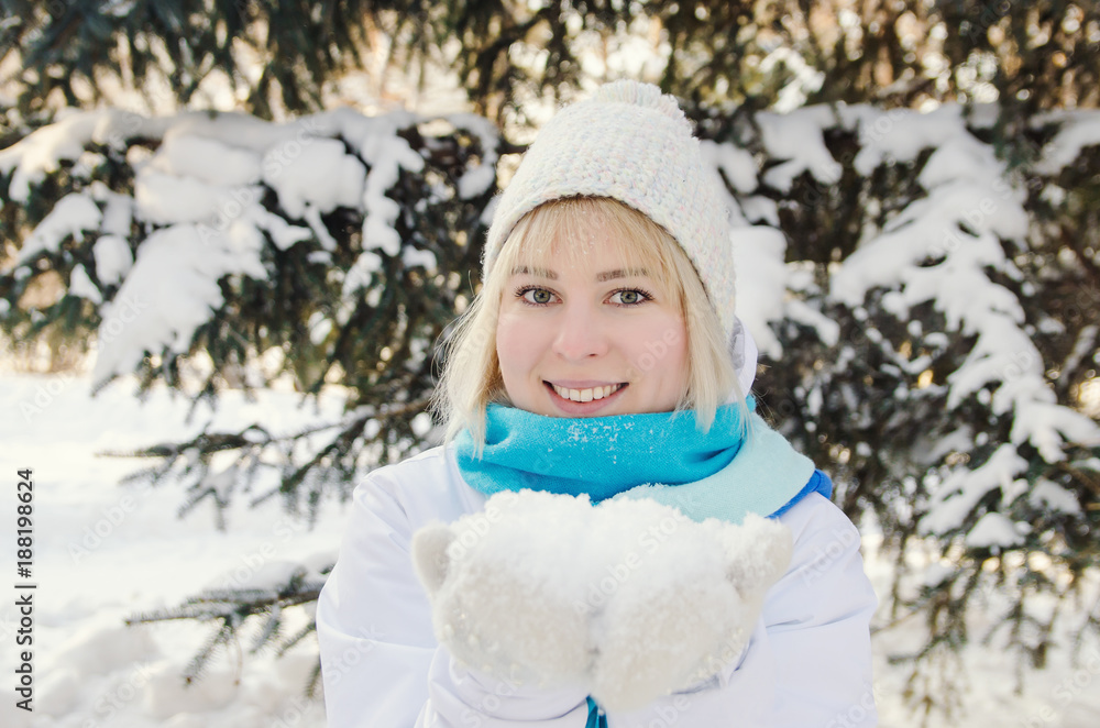 beautiful blond smiling girl holding snow on the palms