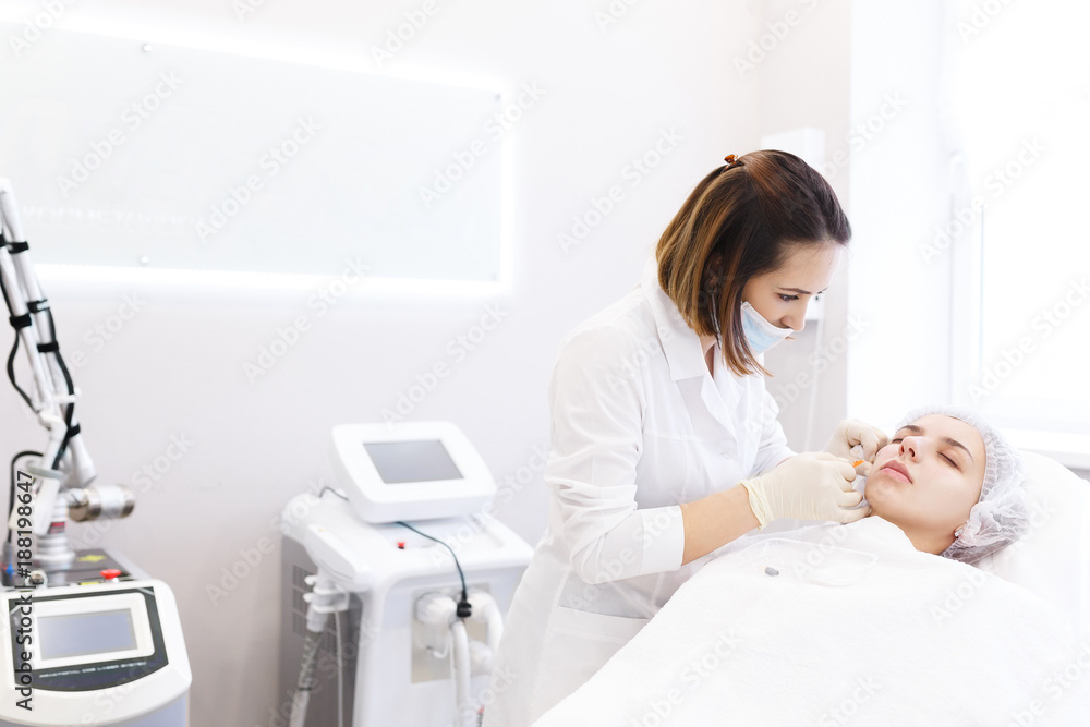 Hardware and Injections cosmetology. Process of facial beauty injections, biorevitalization of female face procedure in a beauty clinic . Cosmetologist works with patient in a white cosmetology office Hardware and Injections cosmetology. Process of facial beauty injections, biorevitalization of female face procedure in a beauty clinic . Cosmetologist works with patient in a white cosmetology office