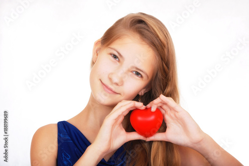 Smiling beautiful teen girl with a symbolic gift in the form of a red heart