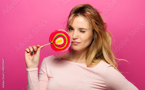 Beautiful young woman with big lollipop on pink background