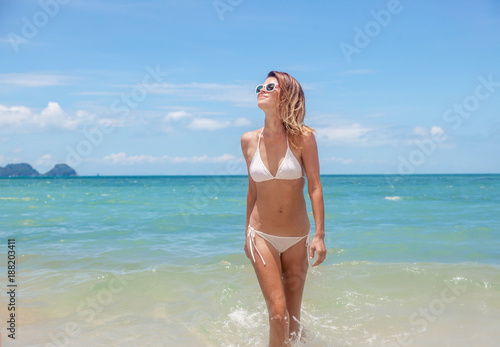 Sexy bikini body woman playful on paradise tropical beach having fun playing splashing water in freedom. Beautiful fit body girl on travel vacation
