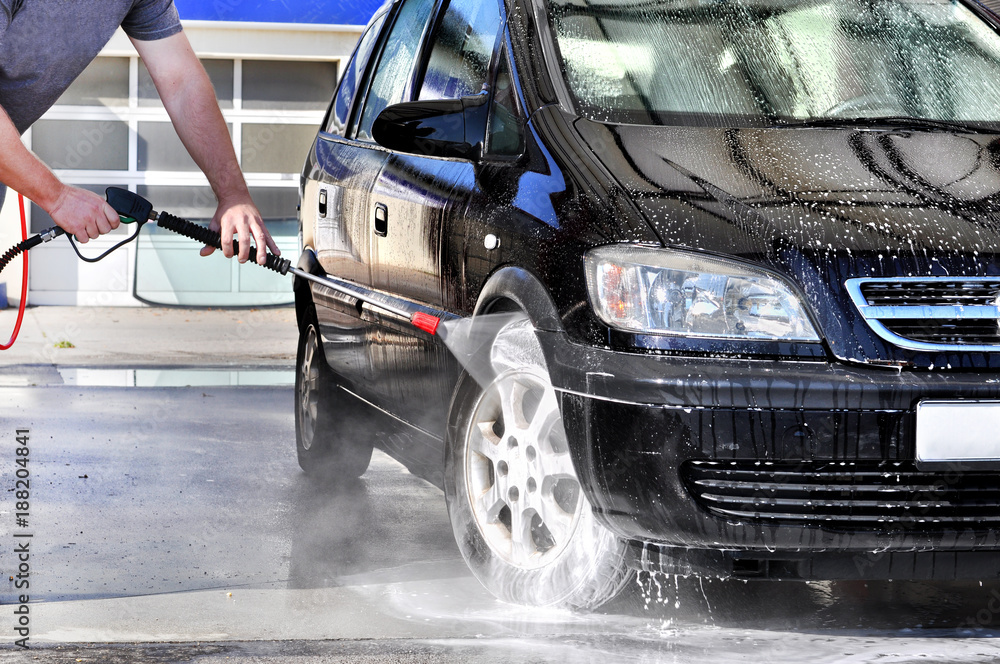 Cleaning Car Using High Pressure Water. Man washing his car under high