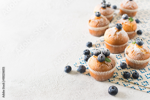 Blueberries muffins or cupcakes with mint leaves on white texture