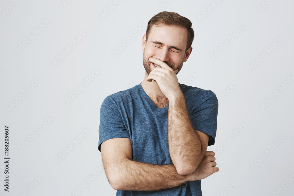 Funny smiling unshaven male wears casual blue clothes, being glad, expresses positive emotions, laughs at joke with closed eyes. People, happiness, positiveness concept Funny smiling unshaven male wears casual blue clothes, being glad, expresses positive emotions, laughs at joke with closed eyes. People, happiness, positiveness concept