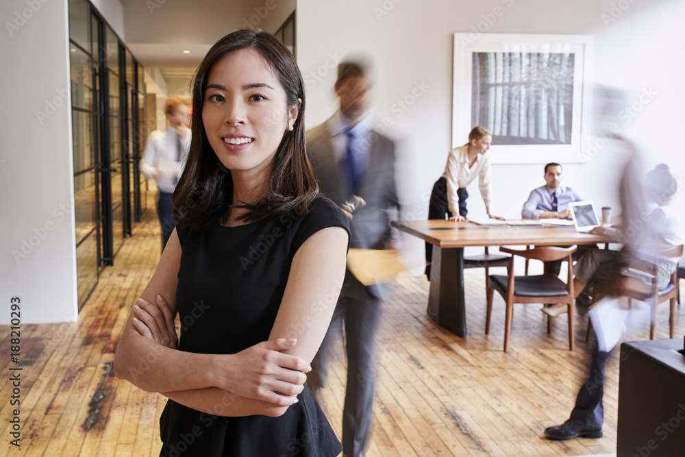 Fototapeta premium Portrait of young Asian woman in a busy modern workplace