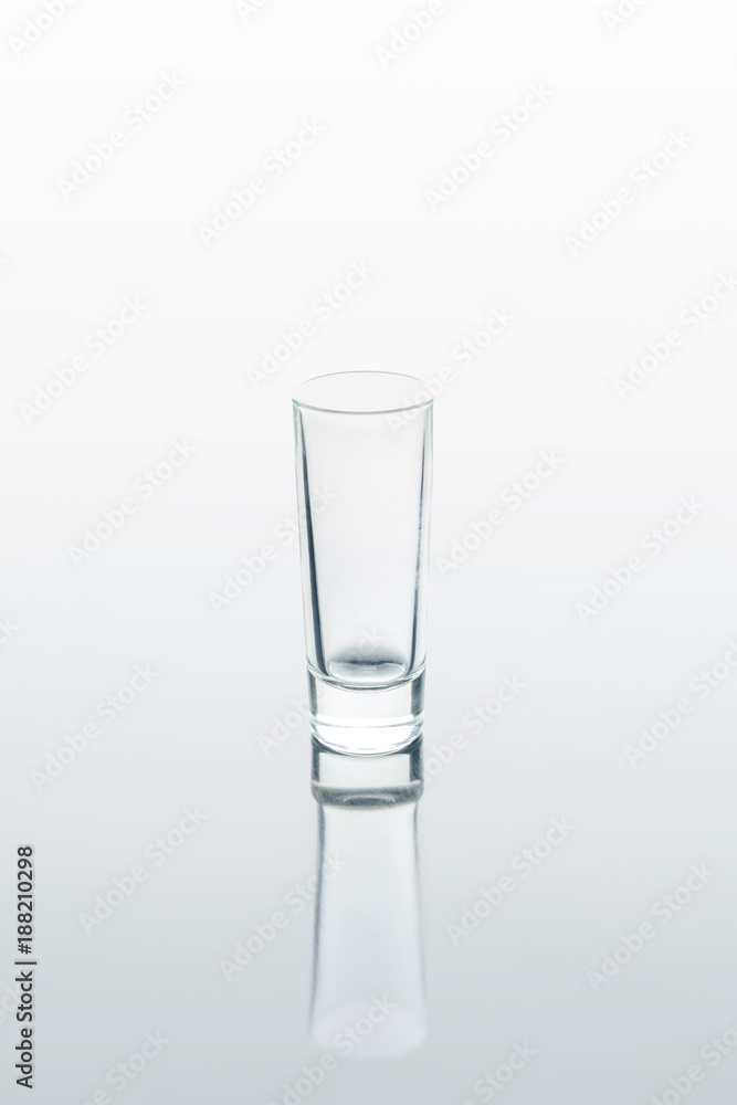 one small glass on white reflecting surface one small glass on white reflecting surface