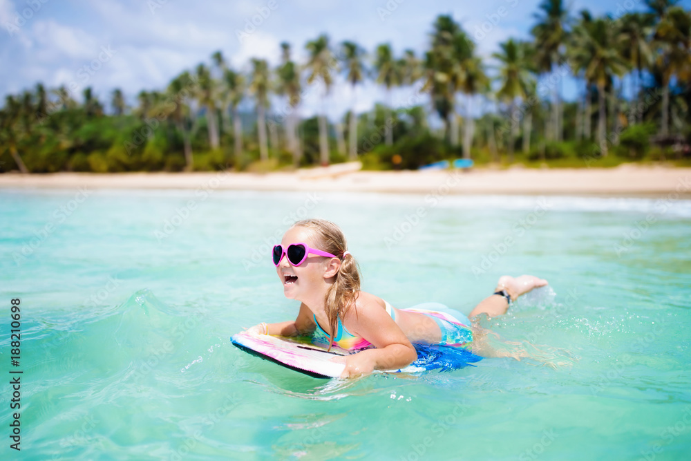 Kids surf on tropical beach. Vacation with child.