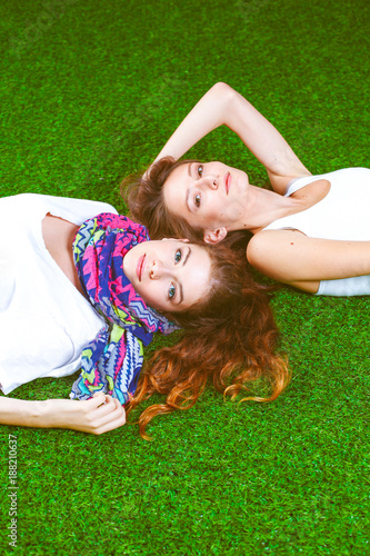 Two pretty girls lying on the fresh green grass