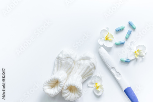 Pregnancy test and booties on white background top view copyspac