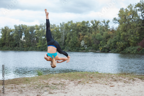 Girl is engaged in sports in nature. She makes somersaults