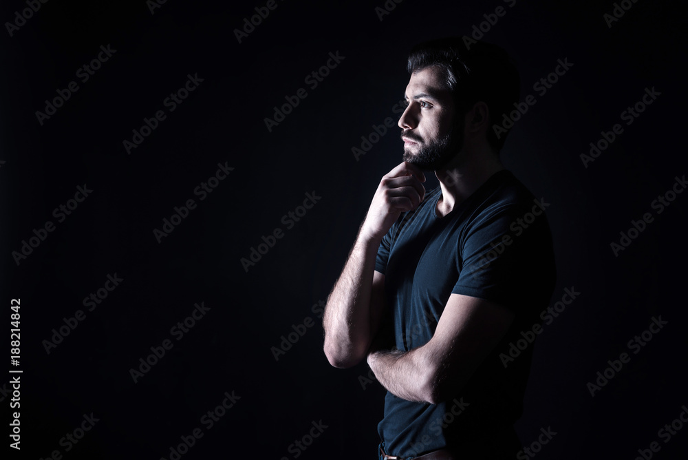 Thoughtful look. Nice pleasant handsome man holding his chin and looking in front of him while being full of thoughts Thoughtful look. Nice pleasant handsome man holding his chin and looking in front of him while being full of thoughts