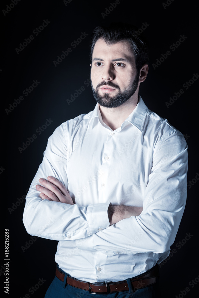 Feeling confident. Serious nice confident man standing cross handed and looking in front of him while focusing on his thoughts Feeling confident. Serious nice confident man standing cross handed and looking in front of him while focusing on his thoughts