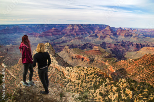 Travel couple standing together hand in hand on the rock in front of amazing view of Grand Canyon, Travelers in love in Grand Canyon National Park