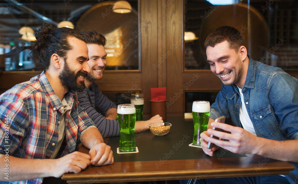 friends with smartphone drinking green beer at pub