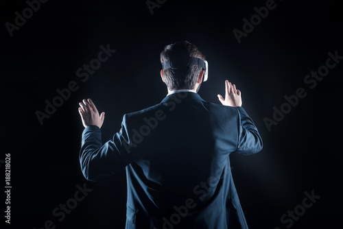 Virtual tech. Professional nice handsome businessman wearing virtual reality glasses and testing wireless technology while standing against black background