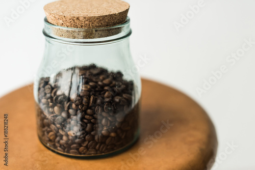 glass bottle with coffee beans and cap on table isolated on white