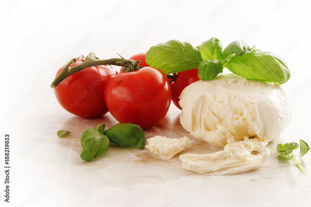 Italian caprese, mozzarella, tomatoes and basil herb on a light marble plate, copy space