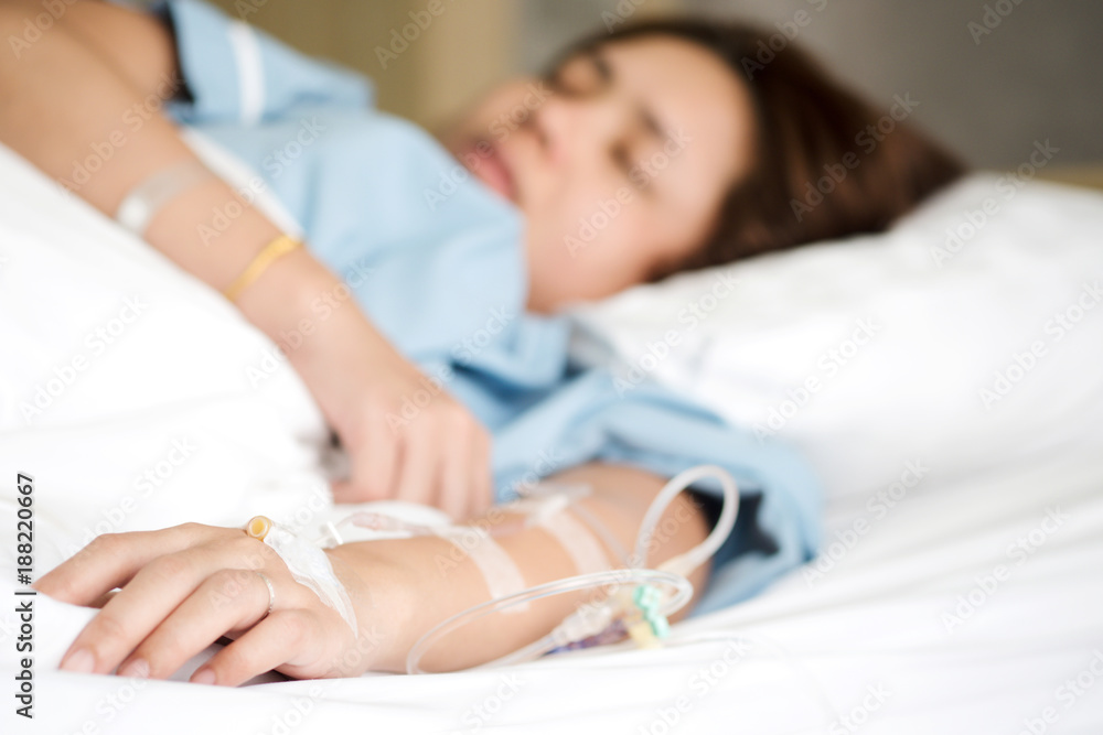 Selective focus on woman patient's hand receiving saline solution by intravenous injection be treated fluid replacement therapy in VIP room in hospital.