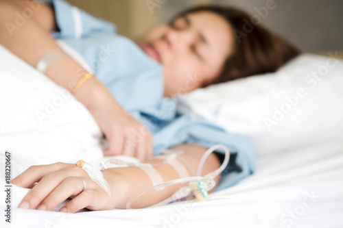 Selective focus on woman patient's hand receiving saline solution by intravenous injection be treated fluid replacement therapy in VIP room in hospital. photo