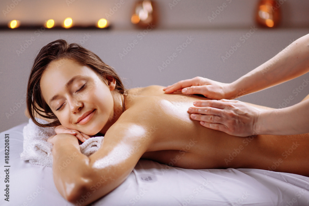 Beautiful woman receiving a relaxing back massage at spa. - obrazy, fototapety, plakaty 