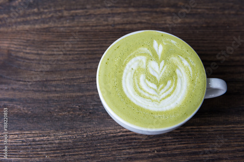 Hot green tea matcha latte in a cup on wooden table, top view
