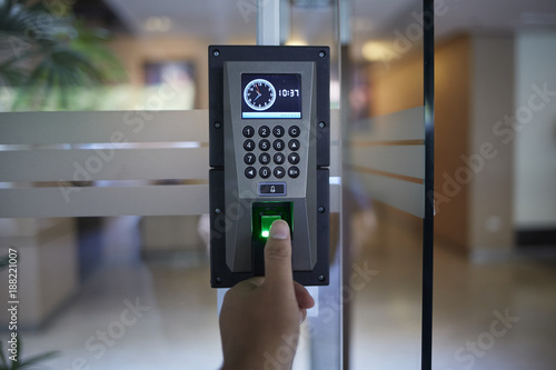 Man or woman push finger down on electronic control machine to access security door system
