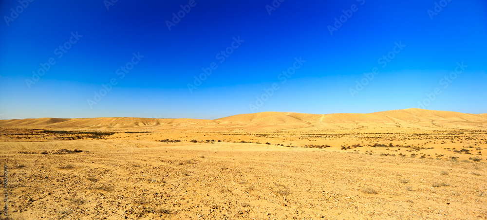 Wide panorama of desert hills under blue sky