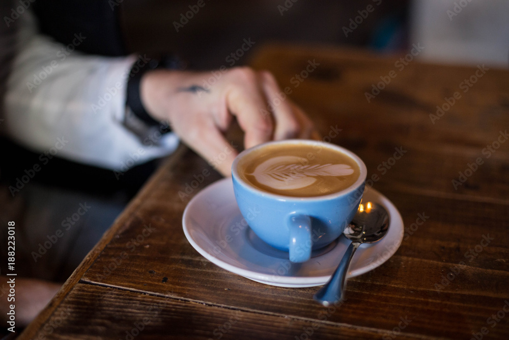 Hipster millennial with hand tattoos gets ready to drink and enjoy fresh and enegretic hot coffee cup, made with organic cow or almond milk and latte art. Early morning routine and caffeine addiction Hipster millennial with hand tattoos gets ready to drink and enjoy fresh and enegretic hot coffee cup, made with organic cow or almond milk and latte art. Early morning routine and caffeine addiction