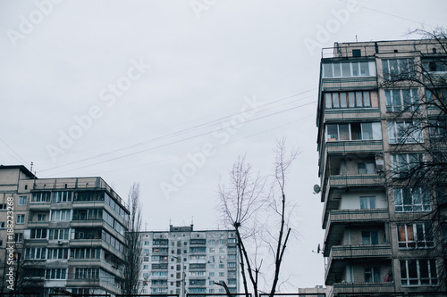 View on dark, grey, smogy and sad winter day in Kiev or Moscow, with tall soviet architecture buildings and naked trees. Cloudy sky, feeling of sadness and depression. WInter mood